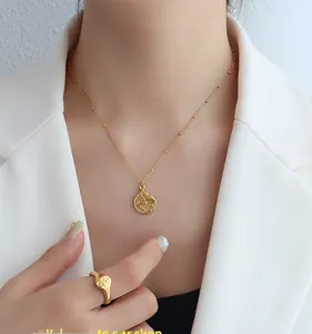 Detail of gold-plated fish tail pendant necklace and wide star engraved ring on model