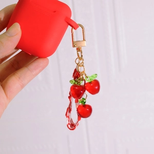 Red cherry keychain with gold chain and matching silicone earbud case for handbags