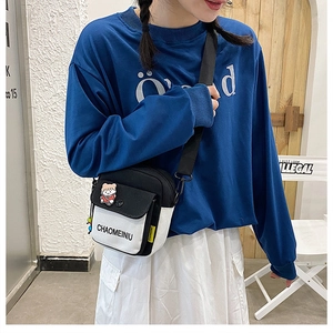 Black and white canvas crossbody bag with cute bear pin shown on a female model