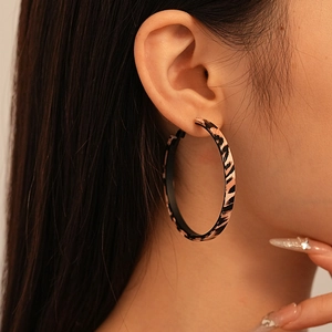 Close-up of leopard print oversized hoop earring worn by a model in vintage style
