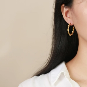 Detailed close-up of twisted rope texture on a golden stainless steel hoop earring