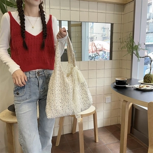 Detail of floral canvas tote bag with white lace bow decoration in a cafe setting