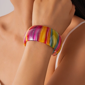 Détail d'un large bracelet manchette en acétate aux rayures arc-en-ciel sur un poignet