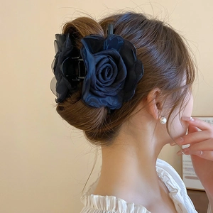 Detail von elegantem schwarzem Organza-Blumen-Haarklammer auf Frisur des Models