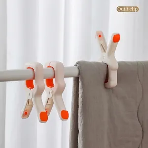 Windproof quilt clip with orange rubber grip securing a grey blanket on a clothesline
