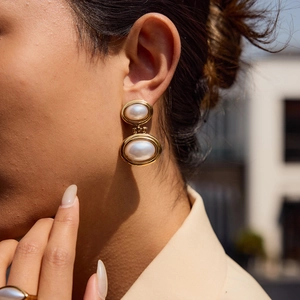Double-layered pearl earrings with gold-plated stainless steel frame worn by model