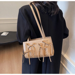 Detail of khaki PU leather shoulder bag featuring intricate lace-up design and silver studs