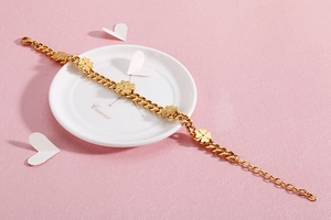 Detailed shot of a gold clover bracelet with crystals on a white ceramic plate