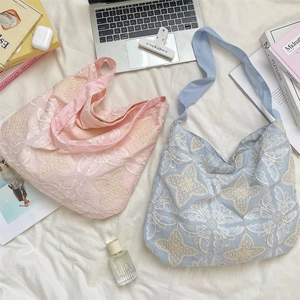 Détail de motifs floraux brodés sur des sacs cabas roses et bleus dans un cadre lifestyle