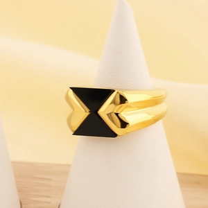 Dettaglio dell'anello in titanio dorato con triangolo in smalto nero su supporto chic