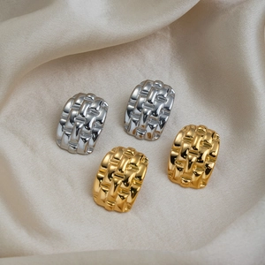 Détail macro de boucles d'oreilles tressées géométriques en or et argent sur soie