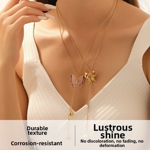 Close-up of double-layer gold necklace with purple enamel butterfly and pearl accents