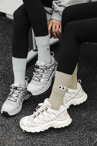 Close-up of candy-colored ribbed mid-tube socks with cute eye embroidery and trail sneakers