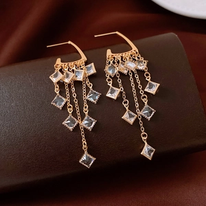 Detailed view of 18K gold plated vintage tassel earrings with square zircons on leather box