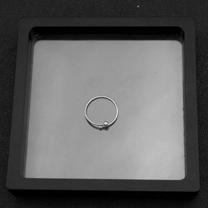 Detailed view of silver irregular open ring with dual small beads in black display box