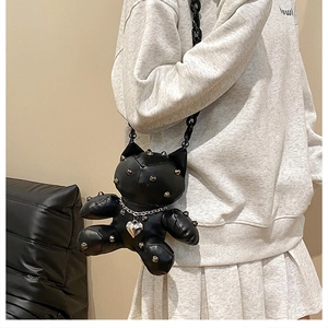 Detail of black leather punk doll crossbody bag with metal rivets and heart necklace charm