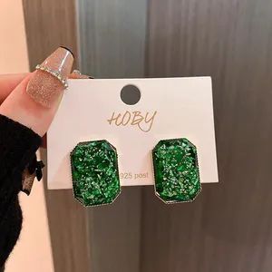 Detailed shot of emerald green rectangular stud earrings with 925 silver posts on a card