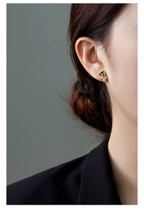 Macro side view of black rose stud earring with gold stem and sparkling zircons