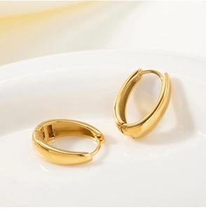 Macro shot of polished 18k gold plated stainless steel U-shaped earrings on white tray