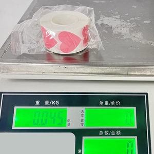 Detail view of pink heart sticker roll on digital scale showing weight of 0.045 kg