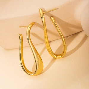 Macro view of gold irregular curved earrings with polished metallic fluid texture