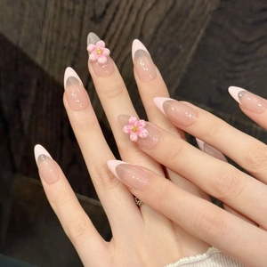 Handmade almond press-on nails with 3D pink flowers and French tip design on a hand