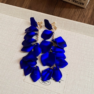 Macro detail of Klein blue petal tassel clip-on earrings with golden chain and matte finish