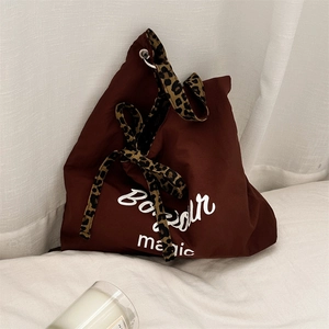 Close-up of leopard print handles and Bonjour magic slogan on brown canvas tote bag