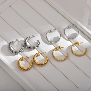 Close-up of gold and silver C-shaped hoop earrings with twisted and diamond-set details