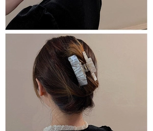 Detail of grey marble ink pattern acetate hair claw clip worn on hair with soft lighting