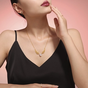 Golden heart zircon angel wing necklace and matching earrings worn by a model