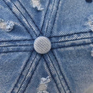Macro view of distressed blue denim baseball cap crown with vintage stitching detail