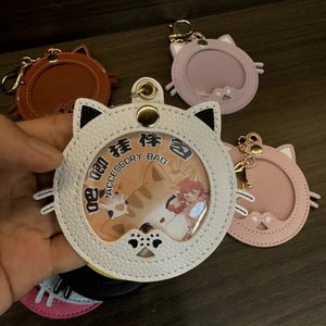 Detail van katvormige lederen badgehouder met rond PVC-venster en gouden metalen gesp