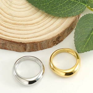 Polished stainless steel band rings in gold and silver finish on wooden base