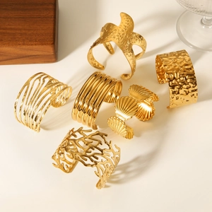 Detailed view of 18K gold plated cuff bracelets featuring ocean motifs and wavy textures