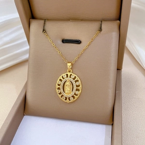 Gros plan du pendentif ovale doré avec gravure de la Vierge Marie et cristaux brillants