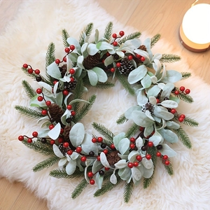 Detail of Christmas wreath with pine cones, red berries and lamb's ear leaves on white rug