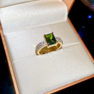 Detail of 18k gold plated ring with emerald cut green stone and pave cubic zirconia