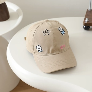 Detail of embroidered cartoon bear and smiling star on khaki cotton baseball cap