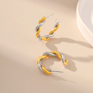 Detailed view of two-tone twisted hoop earrings with gold and silver intertwining textures
