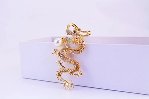 Macro detail of a golden dragon keychain featuring multicolored rhinestones and a white pearl
