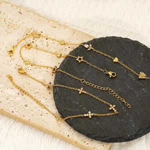 Gold plated stainless steel bracelets with butterfly and star charms on stone background
