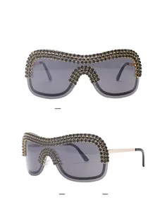 Detail of oversized shield sunglasses featuring black rhinestones and gold chain metal trim