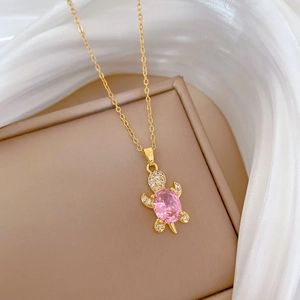 Detail of a gold-plated turtle pendant necklace with a large pink gemstone and sparkling diamonds