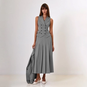 Détail de l'élégant gilet gris à double boutonnage et jupe longue plissée assortie