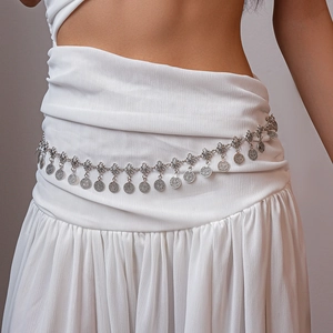 Detail view of vintage silver coin waist chain paired with a white bohemian pleated dress