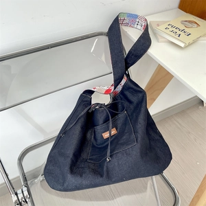 Detail of blue denim tote bag with floral patchwork lining hanging on a chair