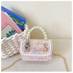Macro detail of kids tweed handbag with pearl handle and floral rabbit decorations