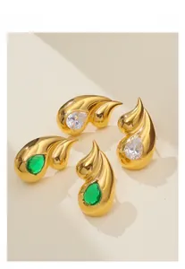 Detailed macro view of 18k gold plated double teardrop earrings with green and clear gemstones