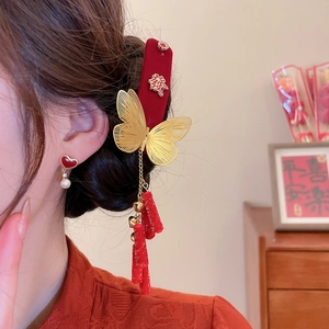 Close-up of a velvet red butterfly hair clip with gold metal accents and red tassels